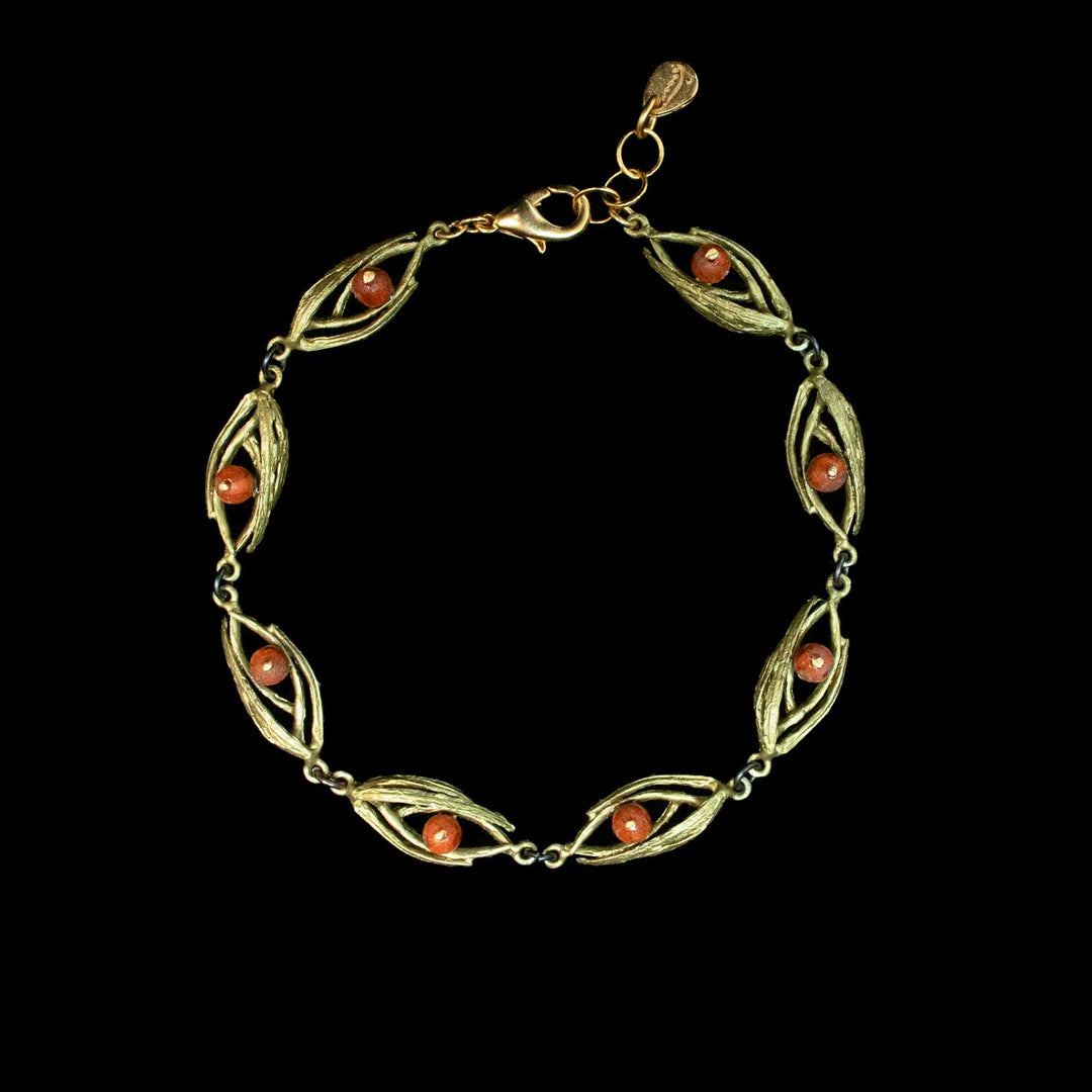 A green-toned bracelet with a leaf-like openwork design and small round orange-red bead accents, displayed on a solid black background.