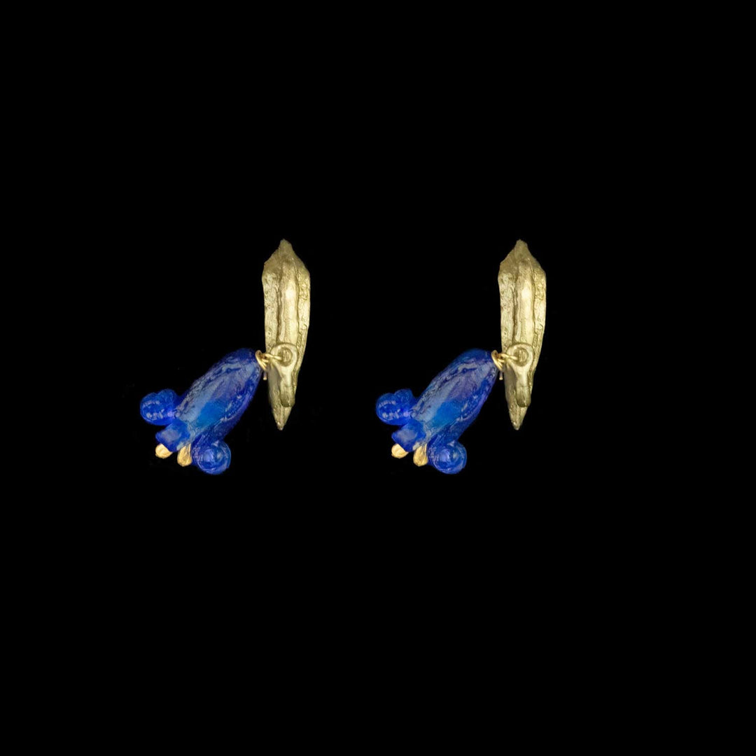 A pair of green post earrings with dangling blueglass flowers each, shown against a solid black background.