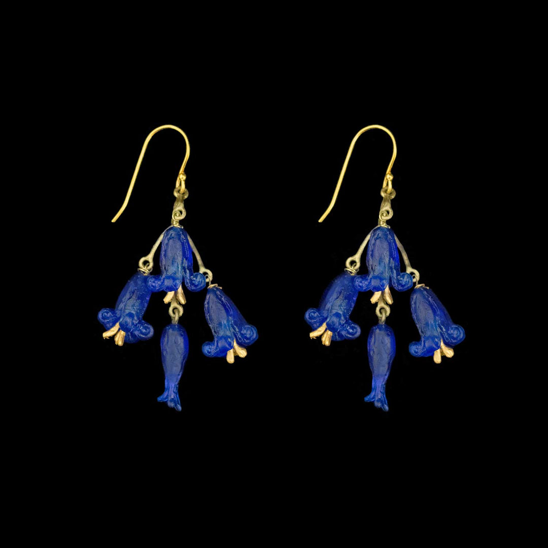 A pair of green-tone and cobalt blue bell-shaped flower drop earrings on a solid black background.
