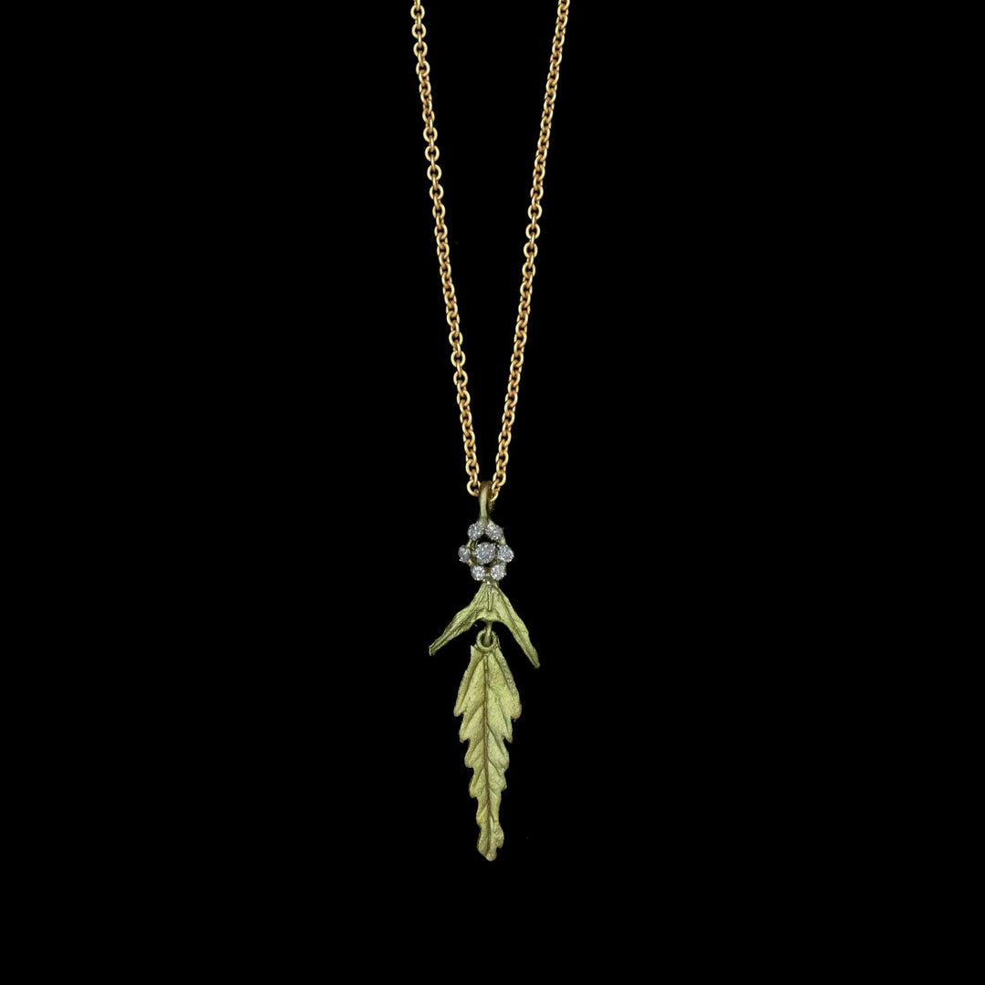 Gold necklace with a leaf-shaped pendant on a black background