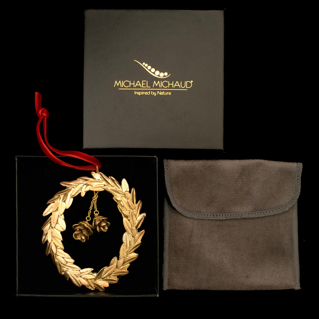 Golden wreath ornament with pinecones, packaging, and pouch on a black background